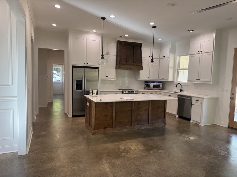Kitchen with a polished stained concrete floor and dark wood island